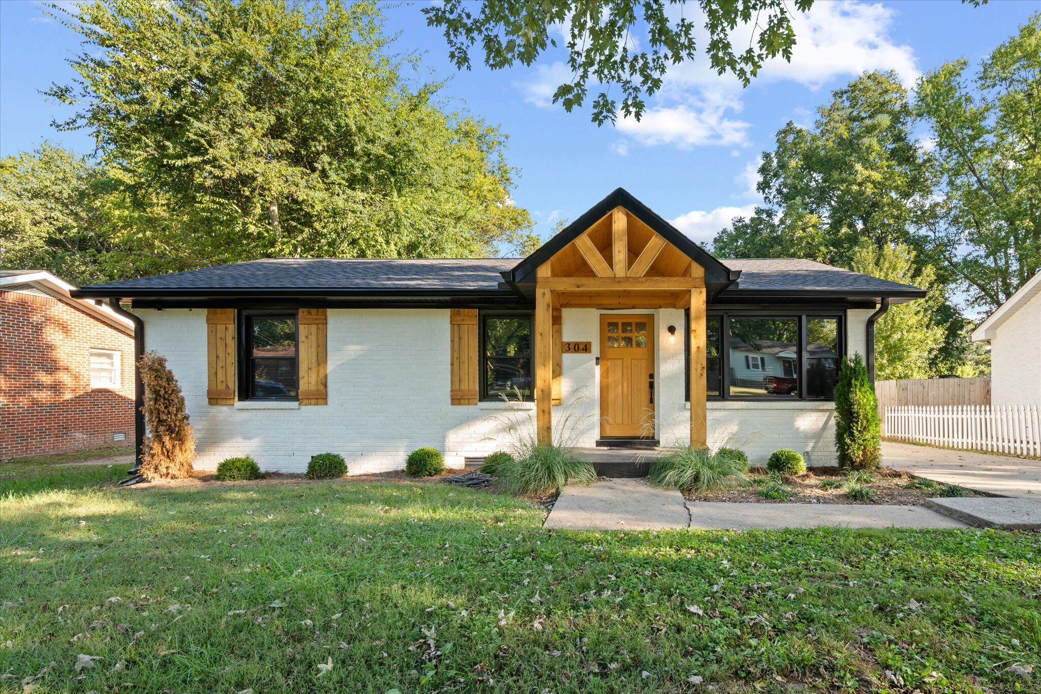 A single-story house with a gabled roof, a front porch with a wooden door, and a small front yard.