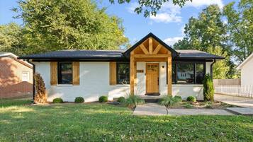 A single-story house with a gabled roof, a front porch with a wooden door, and a small front yard.