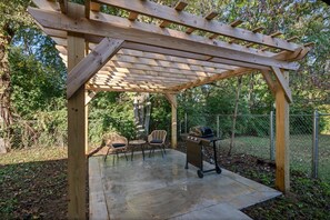 A wooden pergola structure with a grill and seating area. - Newly Renovated Family Retreat (Franklin)