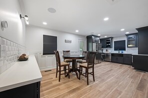 A modern kitchen with a dining area, featuring a round table and chairs, built-in appliances, and a white tiled backsplash. - Newly Renovated Family Retreat (Franklin)