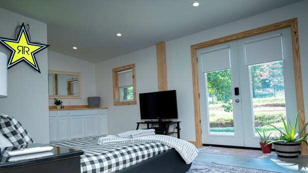 Une chambre à coucher avec un lit, une télévision, un bureau et une grande fenêtre.