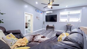 Un salon avec un canapé, un téléviseur et un ventilateur de plafond.