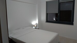 A small, single-bed room with a window, a bedside lamp, and a door. - 2 Rooms Apartment, max 5 Adults, Splendid View on the Beach and the sea (Navodari)