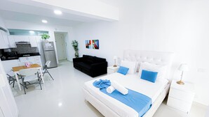 A modern hotel room with a large bed, a separate dining area, and a kitchenette. - STUDIOS ROOFTOP POOL & BEACH (Punta Cana)