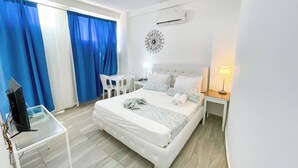 A hotel room with a bed, a desk, a chair, a TV, and a lamp. - STUDIOS ROOFTOP POOL & BEACH (Punta Cana)