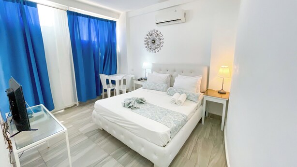 A hotel room with a bed, a desk, a chair, a TV, and a lamp. - STUDIOS ROOFTOP POOL & BEACH (Punta Cana)