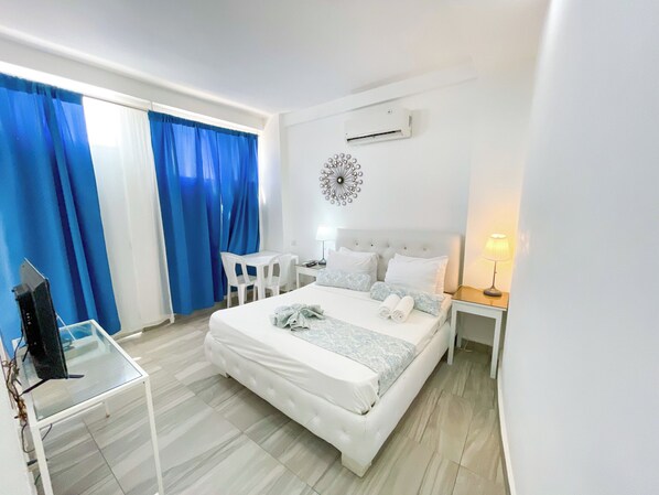 A hotel room with a bed, a desk, a chair, a TV, and a lamp. - STUDIOS ROOFTOP POOL & BEACH (Punta Cana)