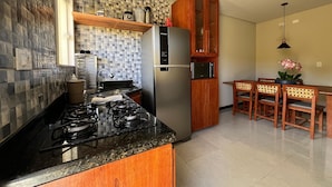 A modern kitchen with a gas stove, stainless steel refrigerator, and wooden cabinets. - Condomínio Tranquilo 350m da Praia (Porto Seguro)