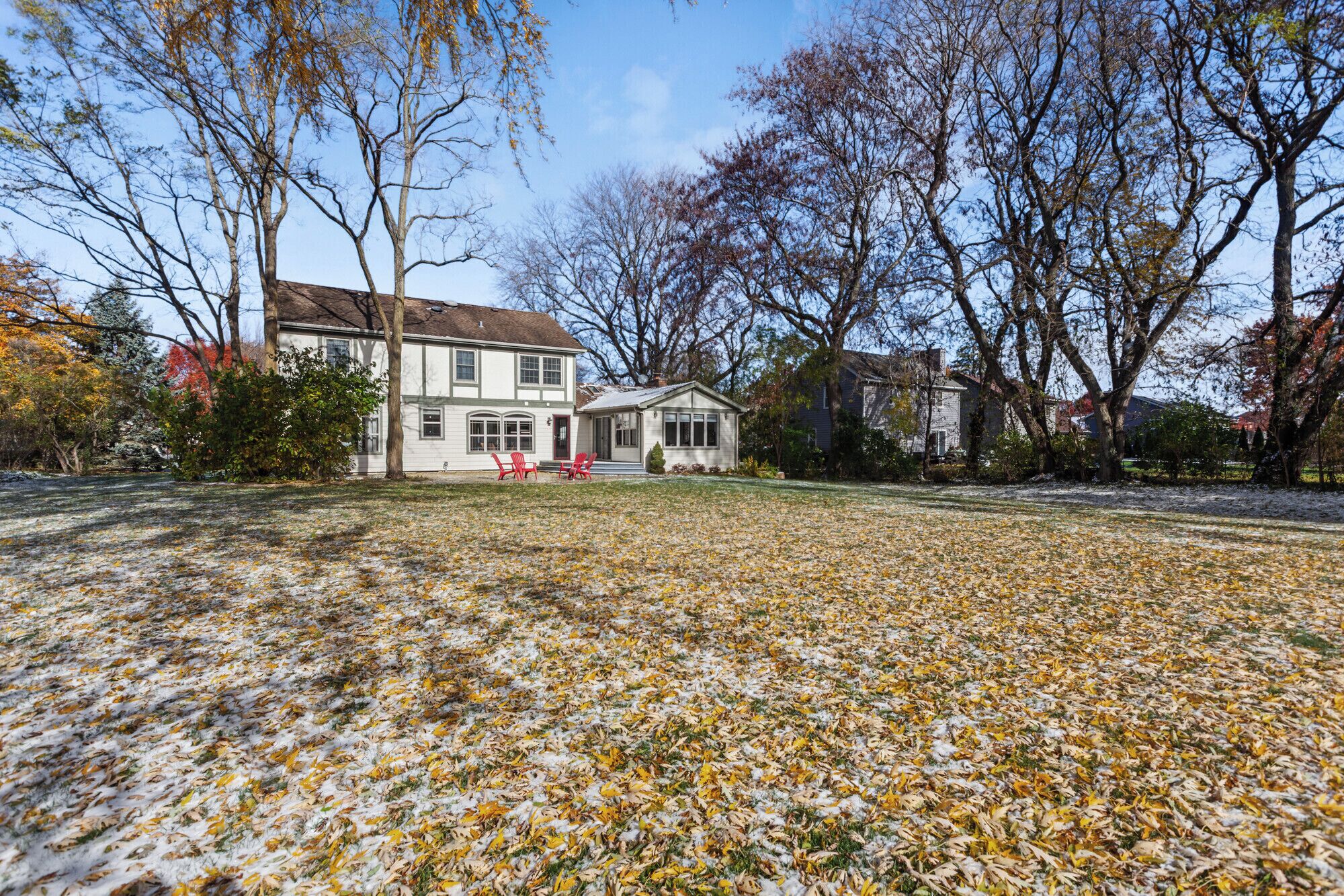 Ein zweistöckiges Haus mit Veranda und einem kleinen angebauten Garagengebäude.