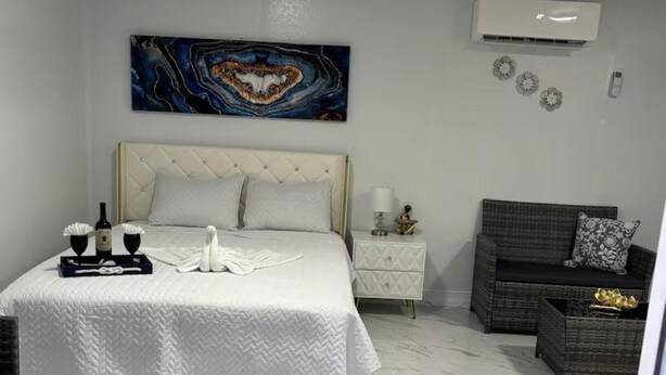 Un dormitorio con cama, mesita de noche y aire acondicionado de pared.