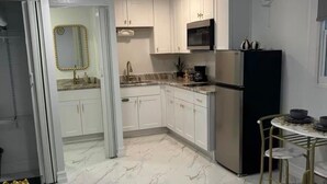 Una cocina moderna con armarios blancos, un refrigerador de acero inoxidable y piso de mármol.