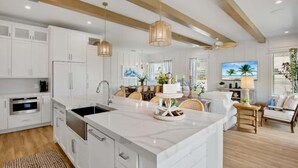 Een moderne keuken met witte kasten, een groot eiland en hanglampen.