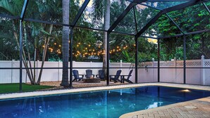 Une piscine offrant une vue dégagée sur les environs, avec une terrasse dotée de chaises et une clôture.