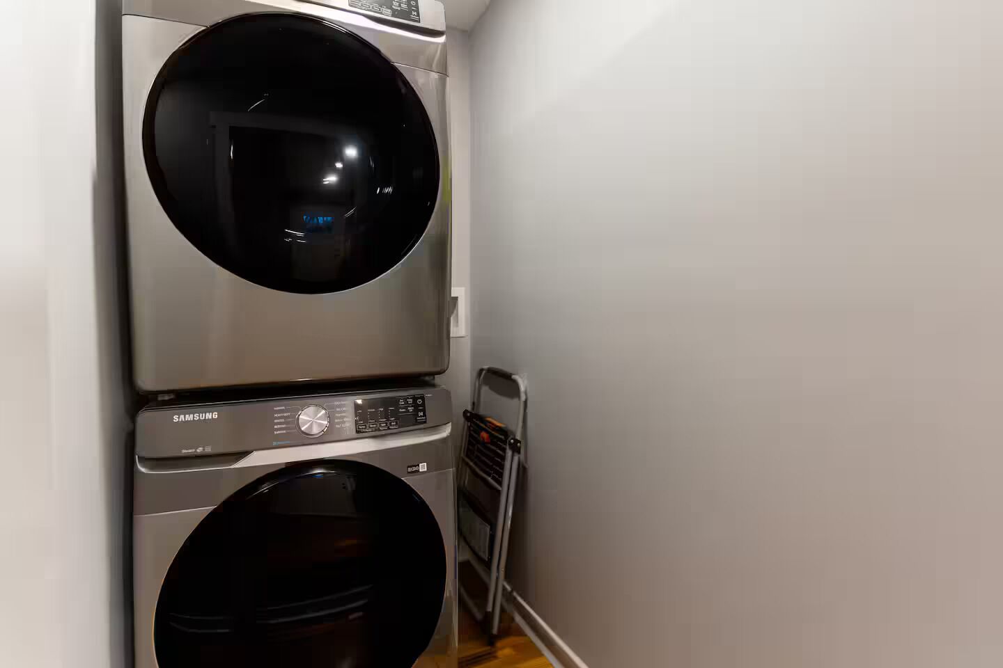 Un área de lavandería compacta con dos lavadoras apiladas y una secadora.
