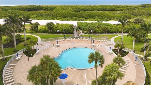 A pool area with a circular design, surrounded by palm trees and a view of the ocean. - Gorgeous 17th fl sunsets @ South Seas 2BR/2BA NEW mattresses updated furnishings (Marco Island)