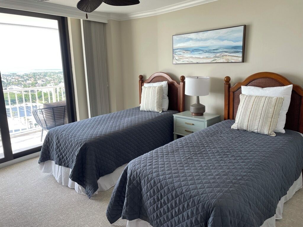 Habitación de hotel con dos camas, un balcón con vistas y un cuadro en la pared.