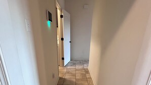 A narrow hallway with beige tiled flooring and white walls.