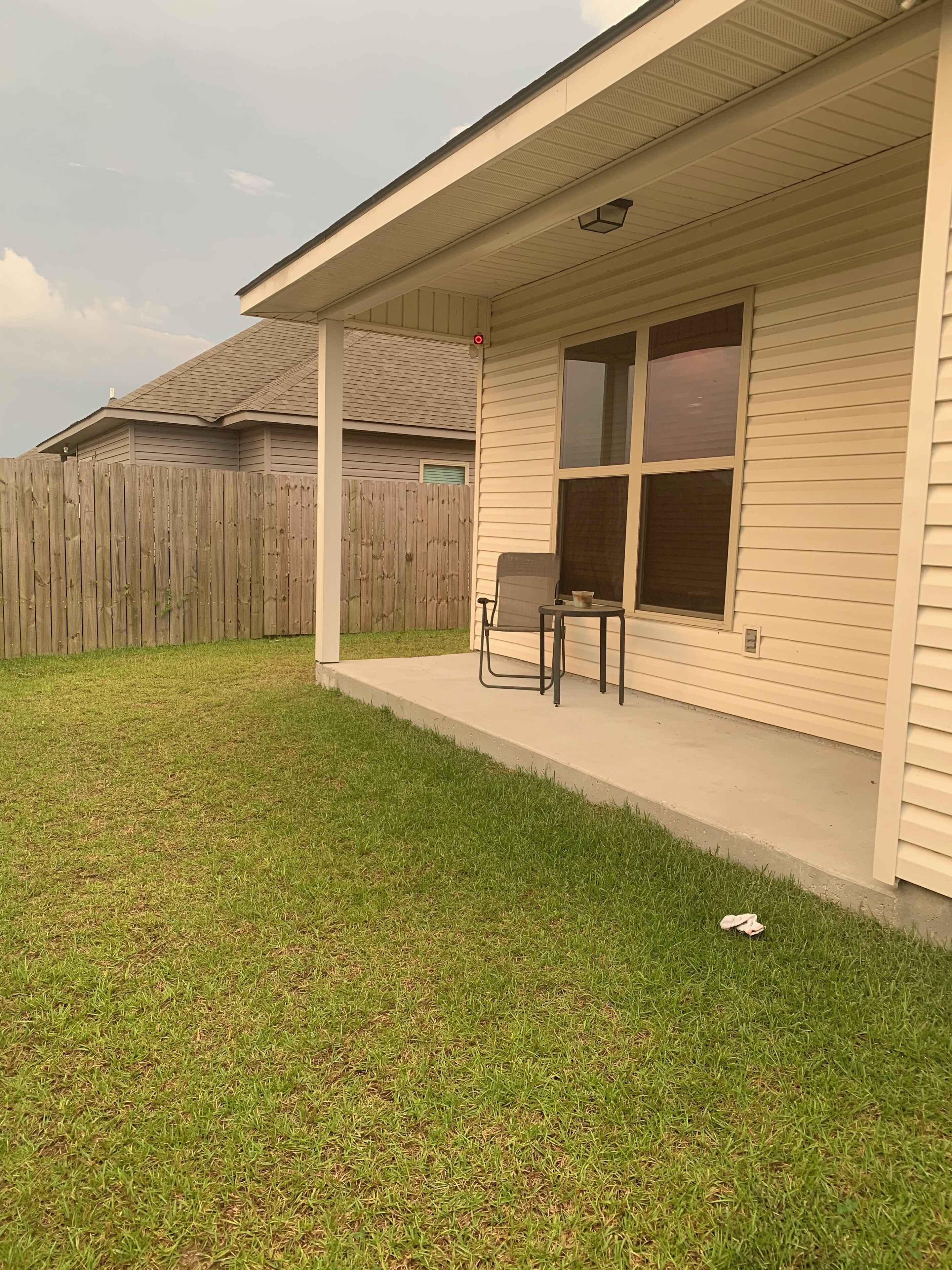 Een huis met een overdekte veranda, een houten omheining en een gazon.