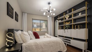 Une chambre à coucher comprenant un lit, des tables de chevet, une armoire et un luminaire au plafond.