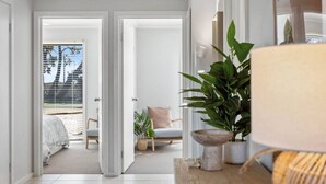 A modern hotel room with a large window, a wooden floor, a bed, a chair, and a potted plant. - Wave Riders in Goolwa Beach (Goolwa Beach)
