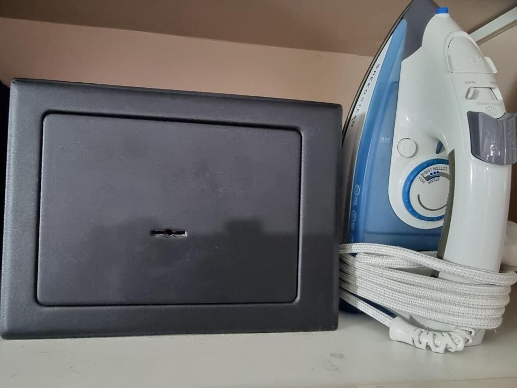 A black appliance, possibly a microwave, and a white and blue iron with a cord.