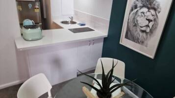 A modern kitchen with white cabinets, a stainless steel sink, and a microwave. There is a framed picture of a lion on the wall.