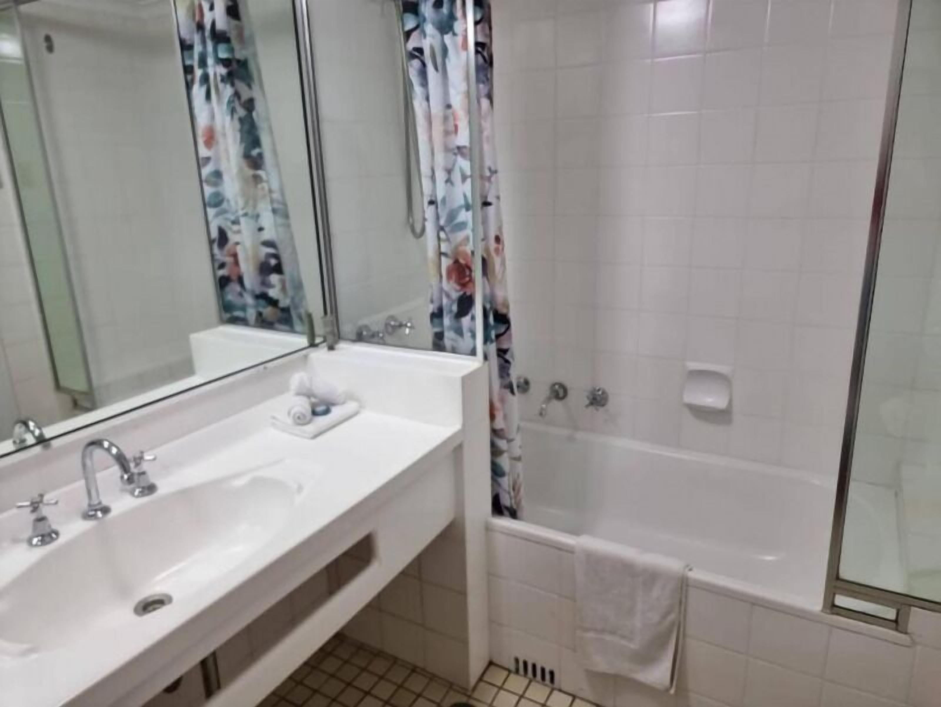 Une salle de bain avec un lavabo blanc, un miroir et une douche.