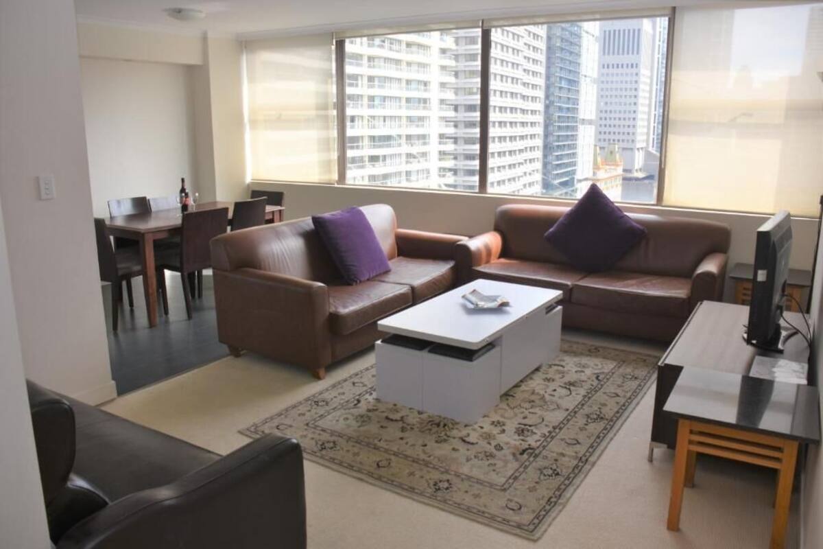 A modern living room with a brown sofa, a white coffee table, and a TV stand.