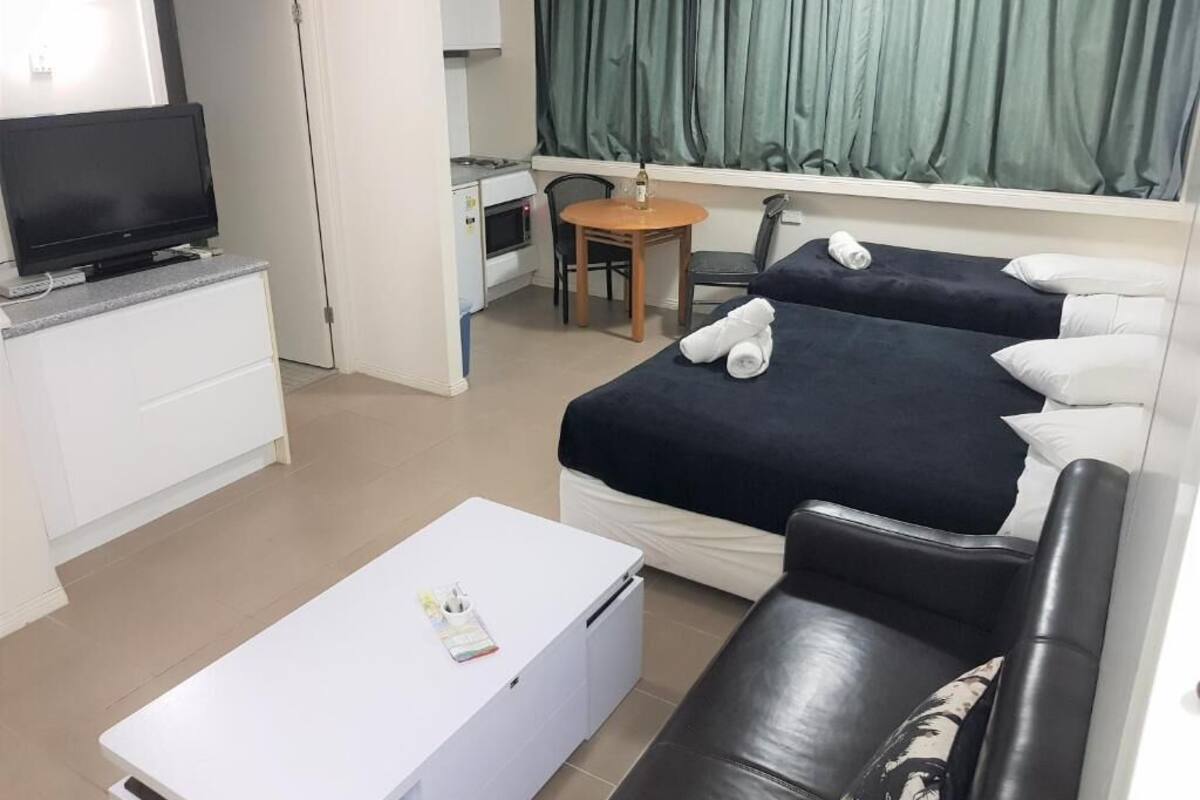 A hotel room with two beds, a TV, a desk, and a chair.