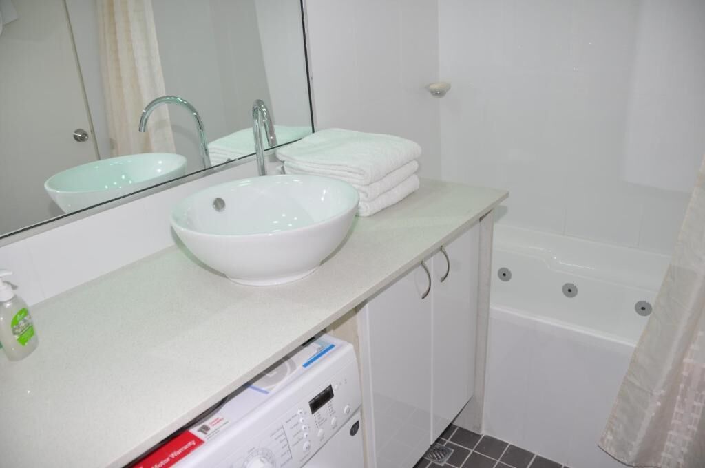 Een badkamer met een witte wastafel, een spiegel, een handdoekhouder en een witte badkuip.