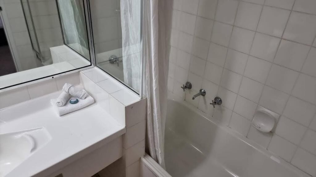 Un bagno con un lavandino bianco, cabina doccia in vetro e uno specchio.
