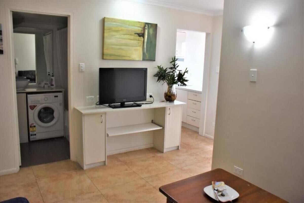 A compact living space with a flat-screen TV, a small kitchenette, and a dining area.