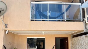 A two-story building with a balcony, a hammock, and potted plants. - casa 4 (Saquarema)