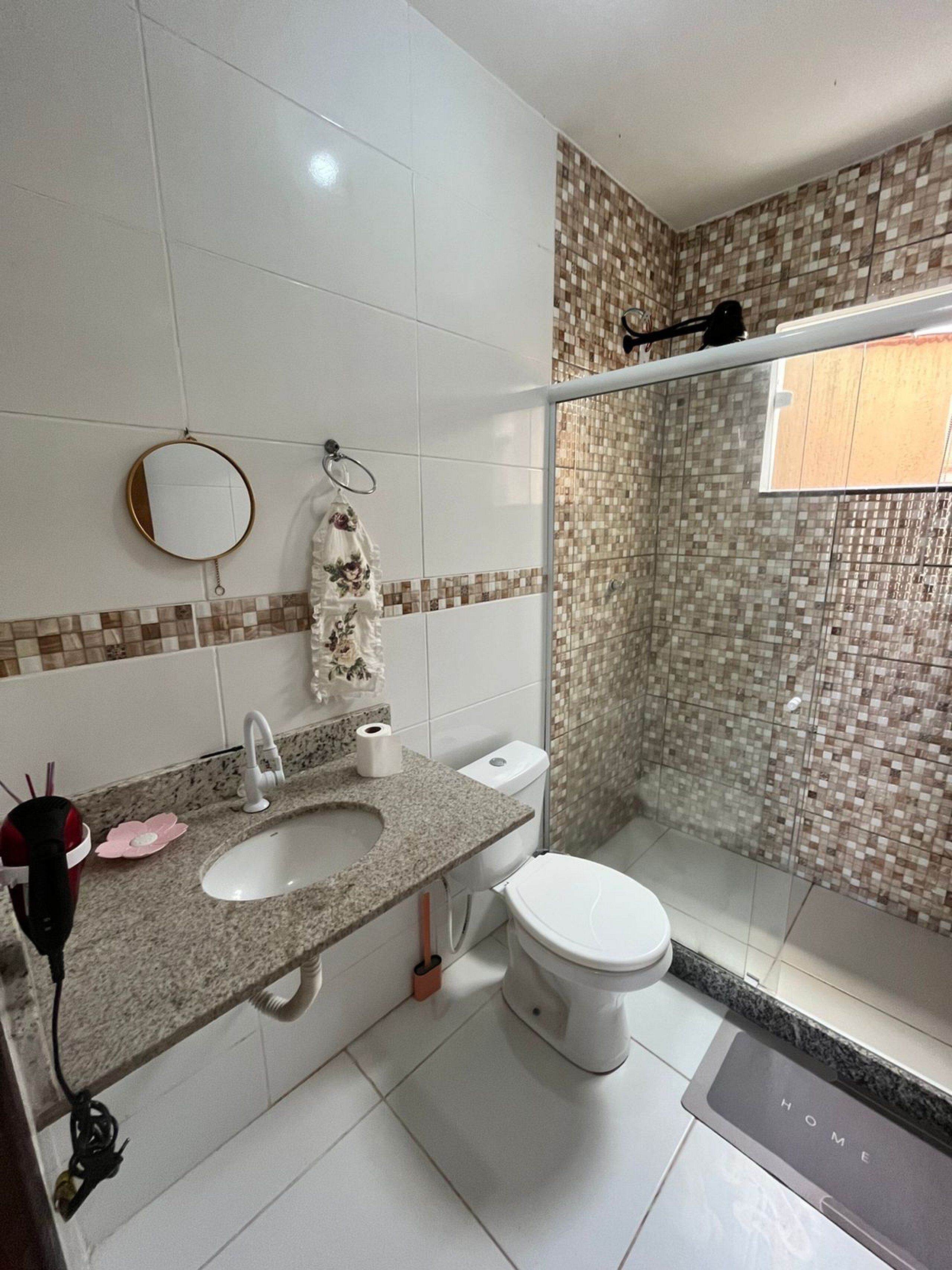 A bathroom with a granite countertop sink, a toilet, and a shower area with mosaic tiles.