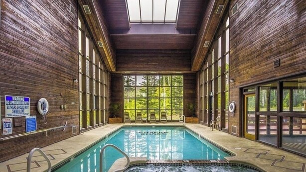 An indoor swimming pool with wooden walls and large windows. - Cozy condo with Pool, Jacuzzi, Sauna, & Fitness Center. Minutes to either lift! (Brian Head)