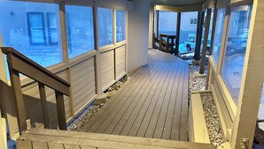 A wooden deck with a staircase leading to a covered area with large windows. - Cozy condo with Pool, Jacuzzi, Sauna, & Fitness Center. Minutes to either lift! (Brian Head)