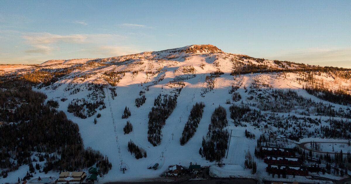 A snow-covered mountain with ski trails and a lodge at the base.