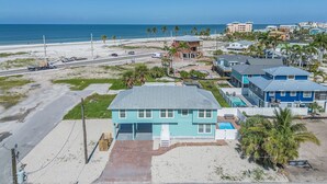 Una propiedad costera con una casa grande, un patio delantero amplio, una piscina y vistas a la playa y al océano.