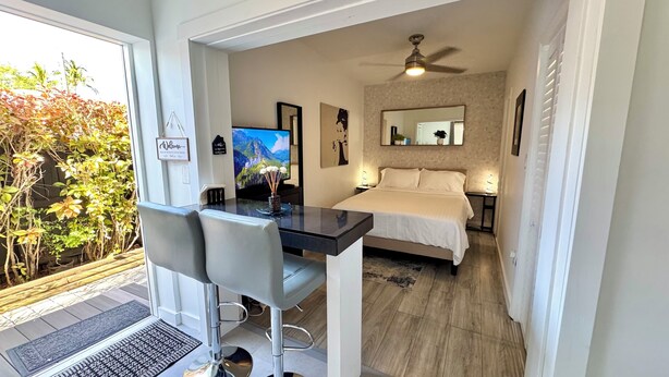 Una camera da letto con un letto, una scrivania con una sedia, una TV e una ventola a soffitto.