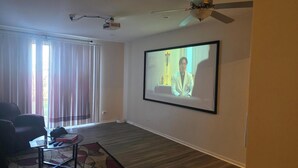 Sala de estar con una pantalla grande, ventilador de techo y proyector.