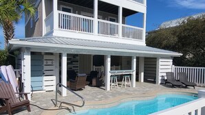 A two-story building with a pool, outdoor seating, and a white fence. - Luxurious home with a Gulf View 4-bedroom with a Private Pool on Cape San Blas (Port St. Joe)