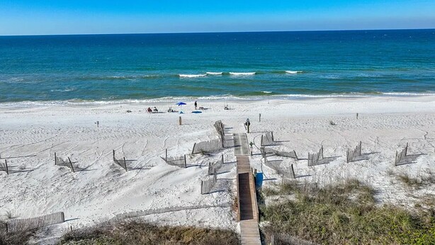 A beach with a wooden boardwalk leading to the shore, clear blue sky, and calm sea. - Luxurious home with a Gulf View 4-bedroom with a Private Pool on Cape San Blas (Port St. Joe)