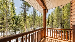 A wooden deck with a railing overlooking a forested area with snow. - Beautiful log lodge. Bring up to 30 Guests! Snowmobile directly from property!!! (Island Park)