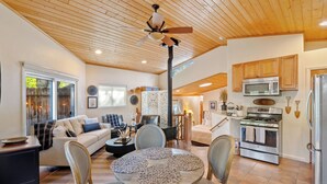 A spacious living room with a wooden ceiling, a round dining table with placemats, a sofa, and a fireplace. - Private Studio-15 miles to SLO and Paso (Atascadero)