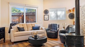 A cozy living room with a sofa, armchair, and a black wood-burning stove. - Private Studio-15 miles to SLO and Paso (Atascadero)