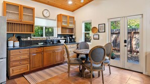 A kitchen with wooden cabinets, a dining table with chairs, a refrigerator, and a clock on the wall. - Private Studio-15 miles to SLO and Paso (Atascadero)