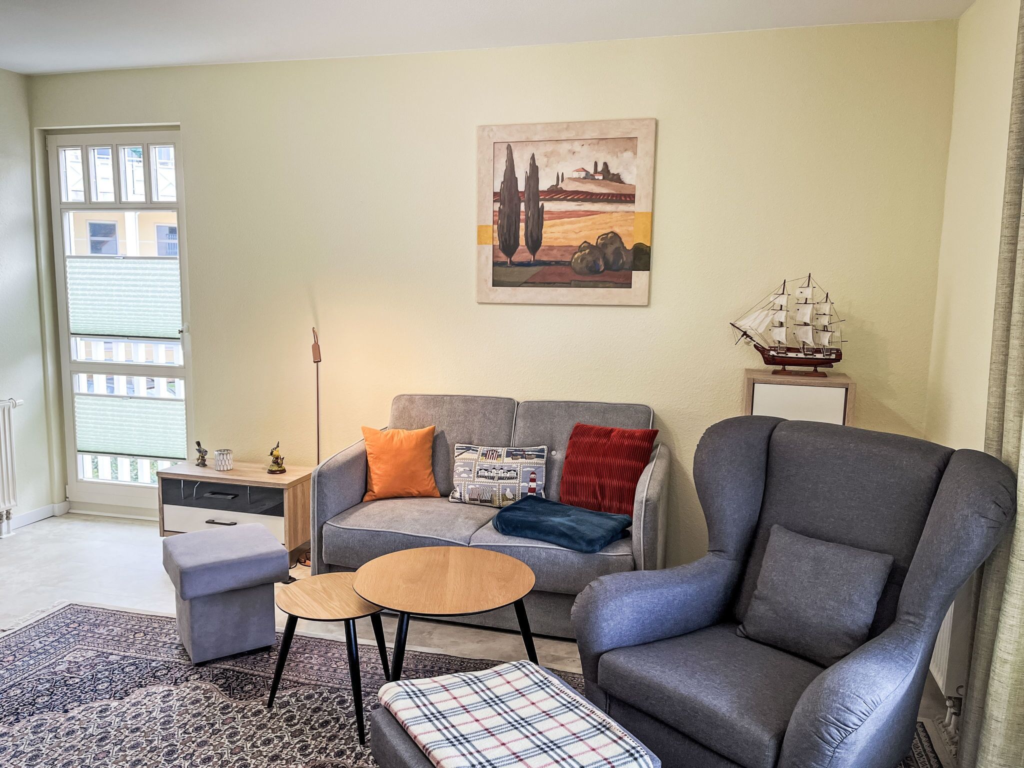 A living room with a grey sofa, a matching armchair, a small coffee table, and a patterned rug.