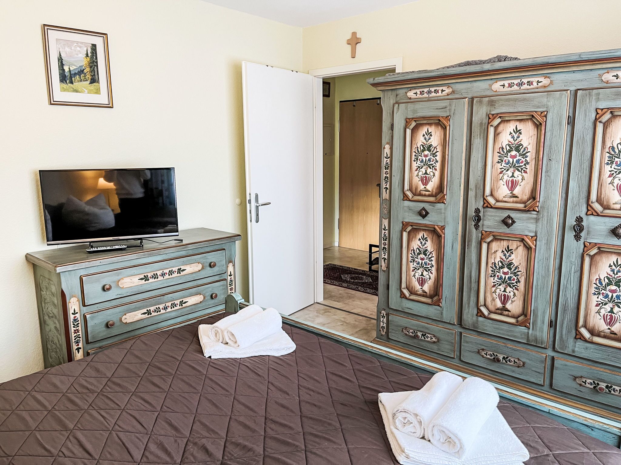 A bedroom with a bed, a dresser, a television, and a wardrobe.