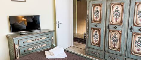 A bedroom with a bed, a dresser, a television, and a wardrobe.