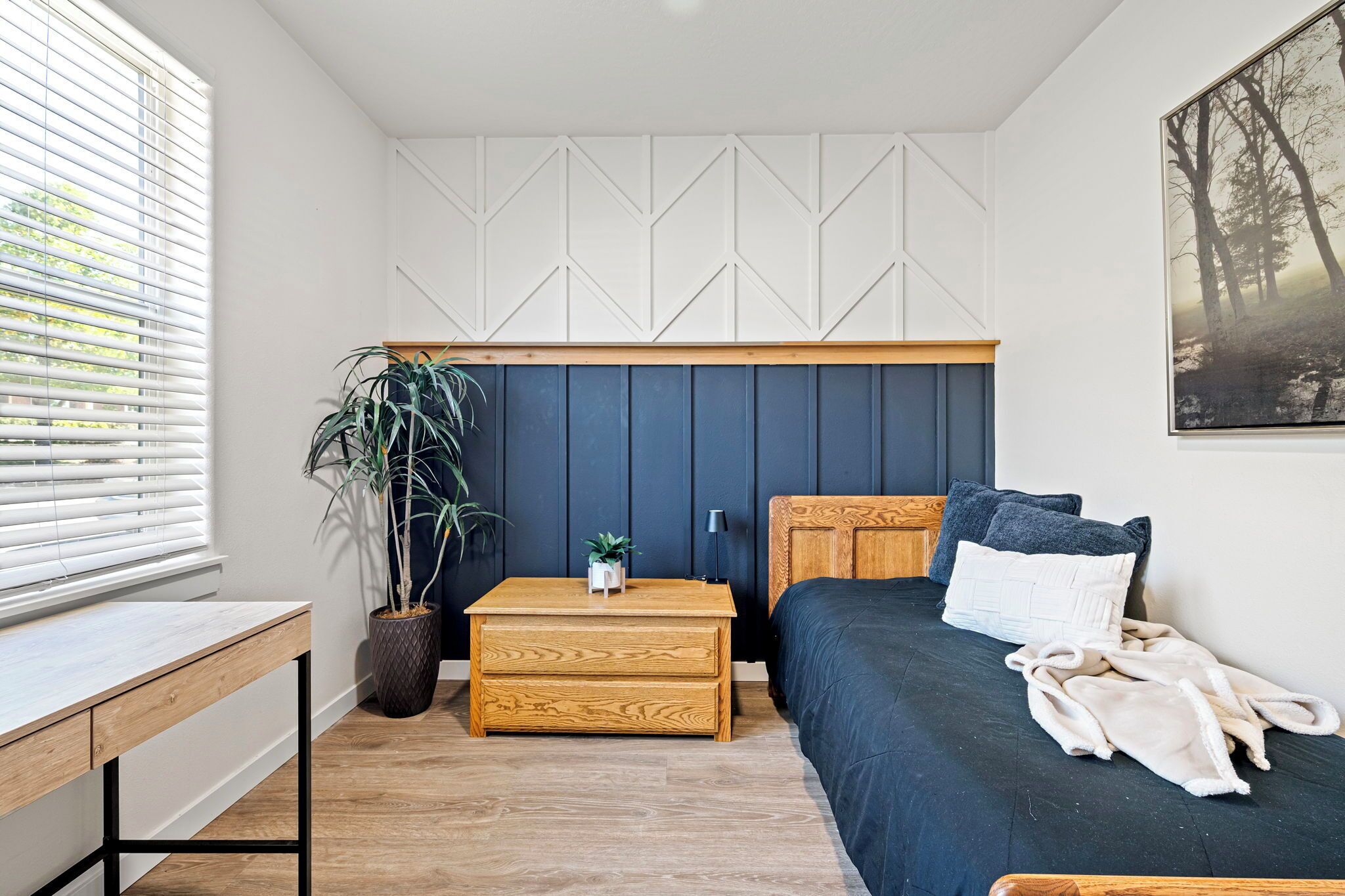 Un dormitorio con cama, mesita de noche y una planta en maceta.